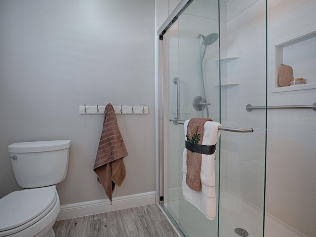 bathroom with a stall shower, wood finished floors, and toilet