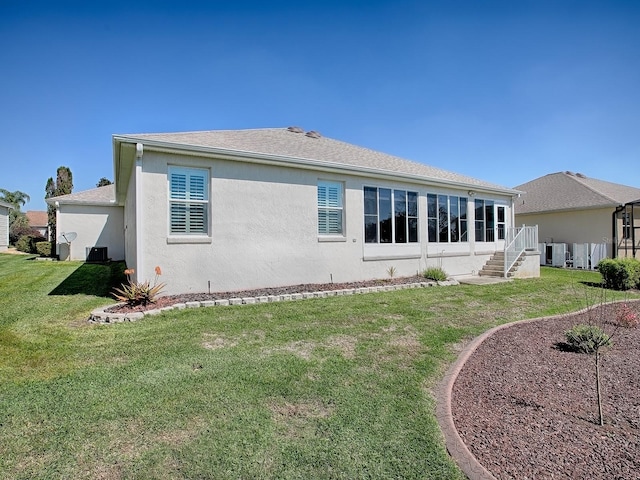 rear view of property with roof with shingles, a yard, and stucco siding