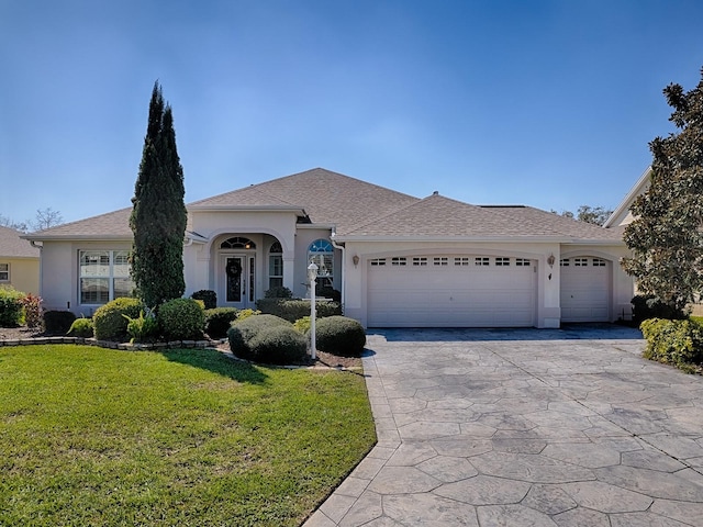 view of front of property with an attached garage, driveway, a front yard, and stucco siding