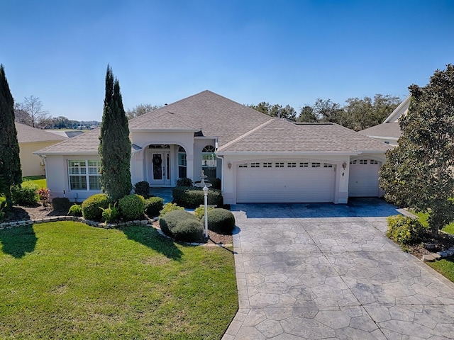 view of front of home featuring driveway, stucco siding, roof with shingles, an attached garage, and a front yard