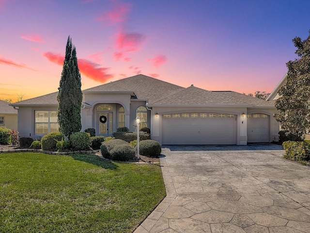 view of front facade featuring a garage, a yard, concrete driveway, and stucco siding