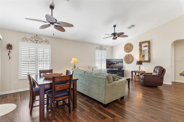 living area featuring arched walkways, dark wood-style flooring, visible vents, and baseboards