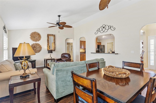 living area with arched walkways, dark wood finished floors, lofted ceiling, ceiling fan, and baseboards