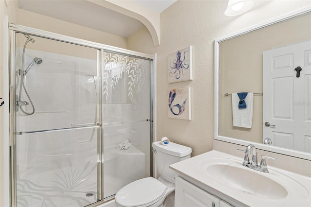 full bathroom with toilet, a textured wall, a shower stall, and vanity