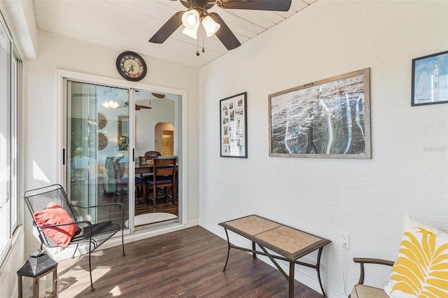 sitting room with arched walkways, dark wood-style flooring, and a ceiling fan