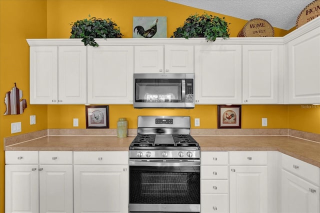 1923 Greeleyville Ter, The Villages, FL 32162 - kitchen featuring lofted ceiling, light countertops, appliances with stainless steel finishes, white cabinetry, and a textured ceiling