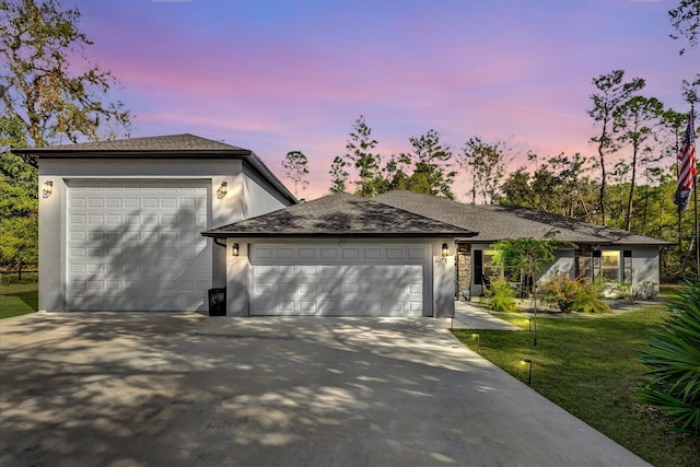 ranch-style house with a garage, driveway, a front lawn, and stucco siding