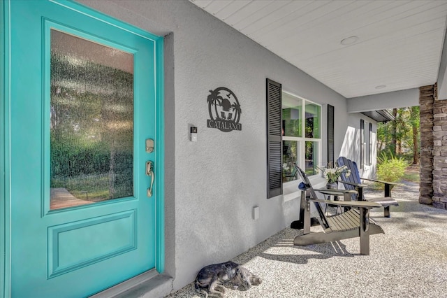 entrance to property featuring a porch and stucco siding