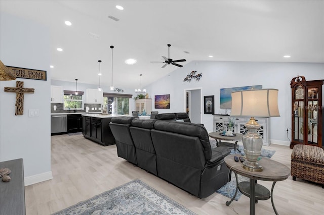 living area featuring light wood-style floors, visible vents, vaulted ceiling, and ceiling fan with notable chandelier