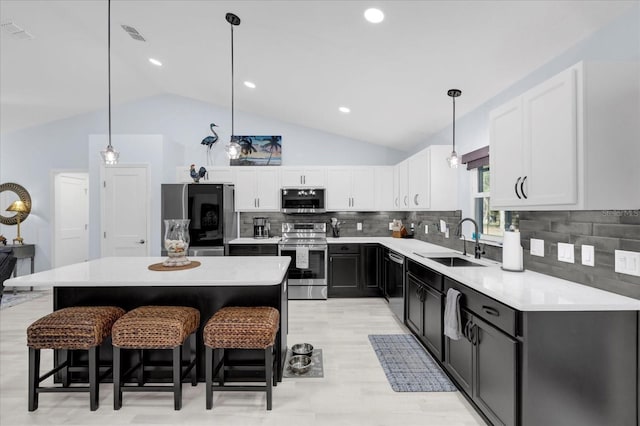 kitchen featuring appliances with stainless steel finishes, a breakfast bar, light countertops, white cabinetry, and a sink