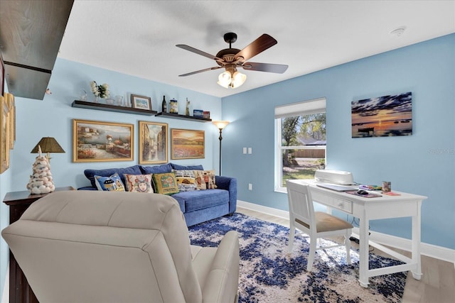 living room featuring baseboards, a ceiling fan, and wood finished floors