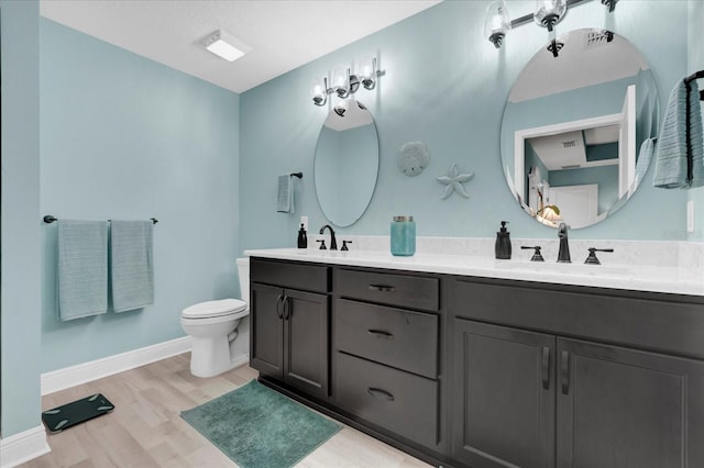 bathroom with double vanity, a sink, toilet, and wood finished floors