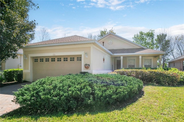 ranch-style house featuring a garage, a front yard, and stucco siding