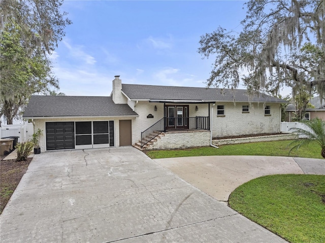 view of front of house featuring concrete driveway, brick siding, a chimney, and a front lawn