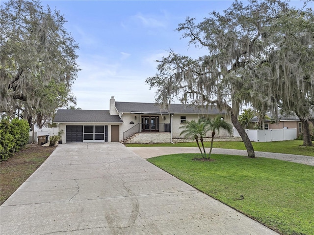 view of front of property with concrete driveway, a chimney, an attached garage, fence, and a front yard