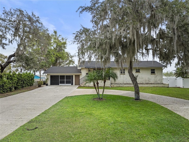 view of front of property featuring a garage, concrete driveway, fence, and a front lawn