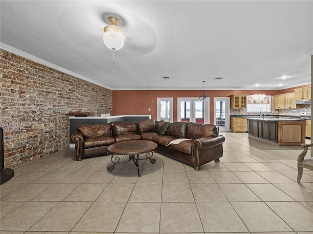 living room featuring light tile patterned floors, brick wall, visible vents, and crown molding