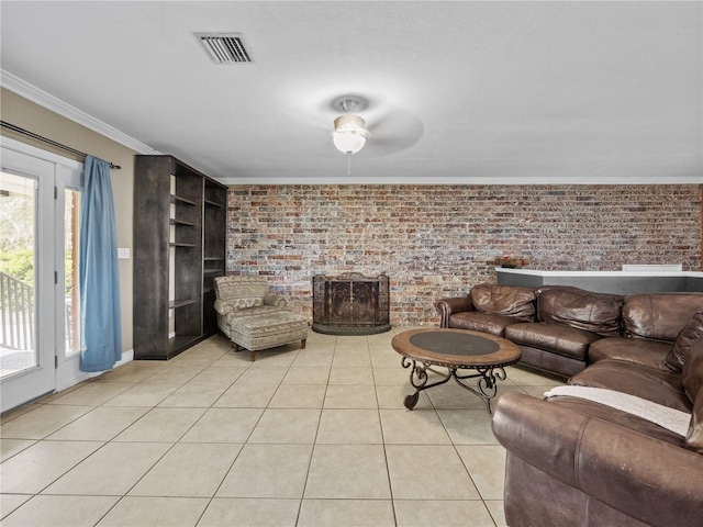 living room featuring light tile patterned floors, visible vents, brick wall, crown molding, and a fireplace