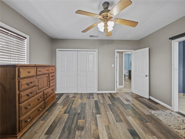 unfurnished bedroom featuring a closet, wood finished floors, visible vents, and baseboards