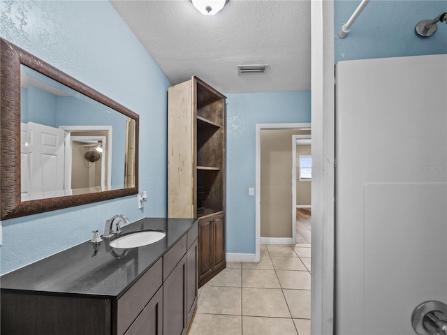 bathroom featuring a textured ceiling, vanity, baseboards, visible vents, and tile patterned floors