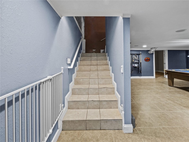 stairs featuring billiards, a textured wall, tile patterned flooring, and baseboards