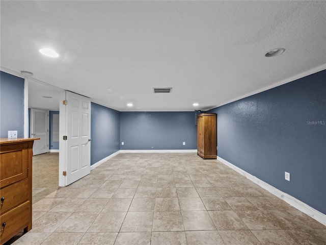 finished below grade area with light tile patterned floors, visible vents, baseboards, a textured wall, and a textured ceiling