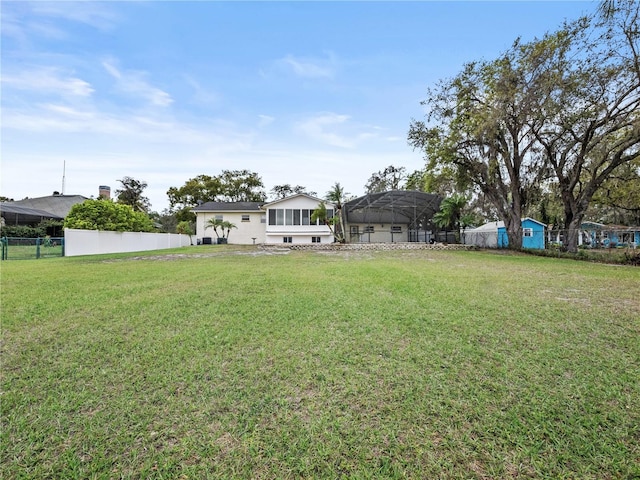 view of yard with glass enclosure and fence