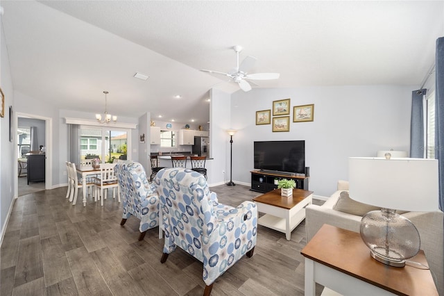 living area with ceiling fan with notable chandelier, lofted ceiling, baseboards, and wood finished floors