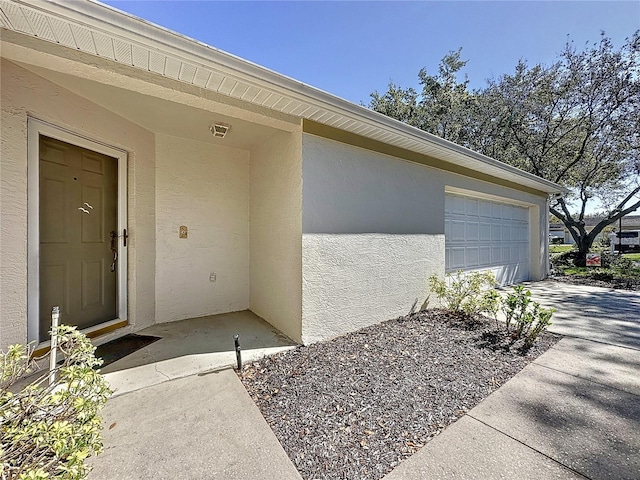 doorway to property featuring a garage and stucco siding