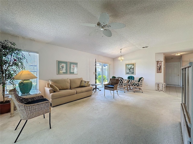 living room featuring ceiling fan, a textured ceiling, light colored carpet, visible vents, and vaulted ceiling