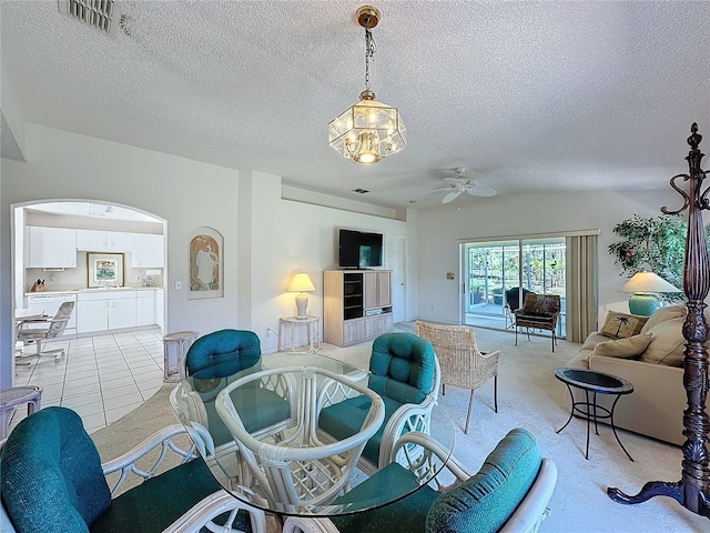 living area with arched walkways, light colored carpet, visible vents, ceiling fan, and a textured ceiling