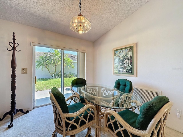 dining room featuring lofted ceiling, a textured ceiling, and carpet flooring