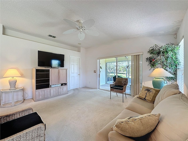 living area featuring a textured ceiling, carpet, visible vents, and a healthy amount of sunlight