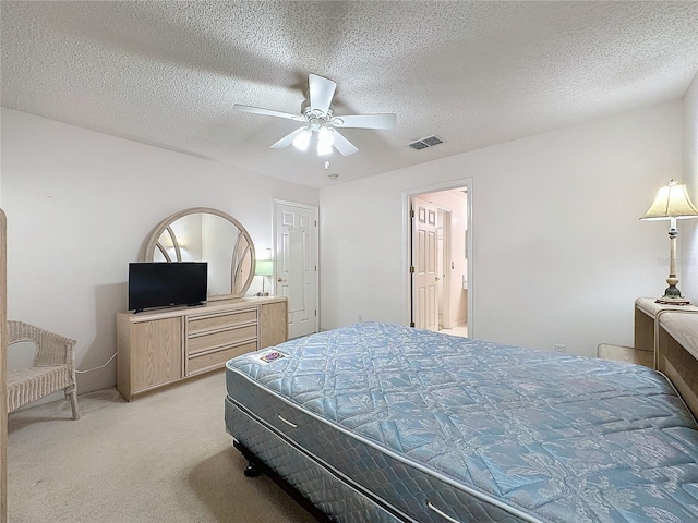 bedroom with a textured ceiling, visible vents, a ceiling fan, and light colored carpet