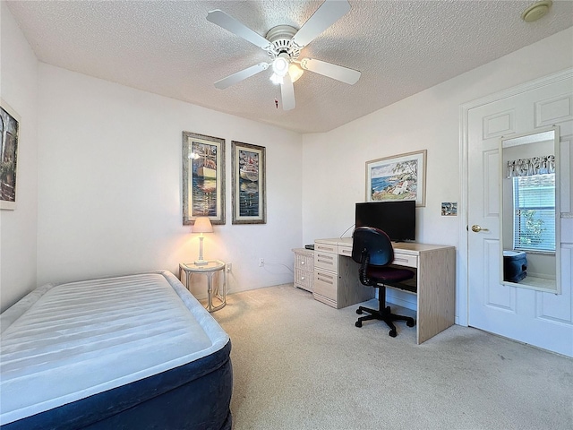 bedroom with a textured ceiling, ceiling fan, and light colored carpet