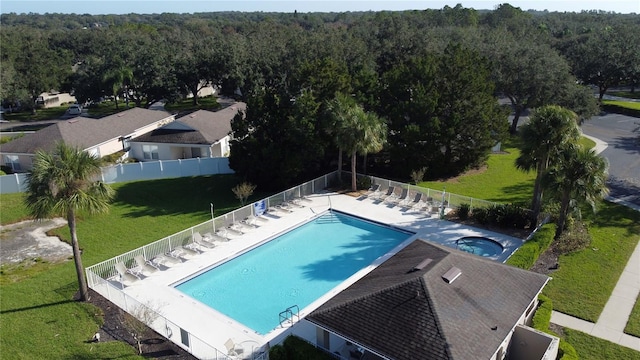 community pool with a patio, fence, and a view of trees