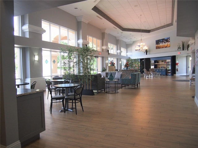 dining area featuring an inviting chandelier, a high ceiling, a raised ceiling, and wood finished floors