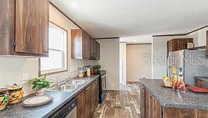 kitchen with dark wood-style flooring, brown cabinets, stainless steel appliances, dark countertops, and a sink