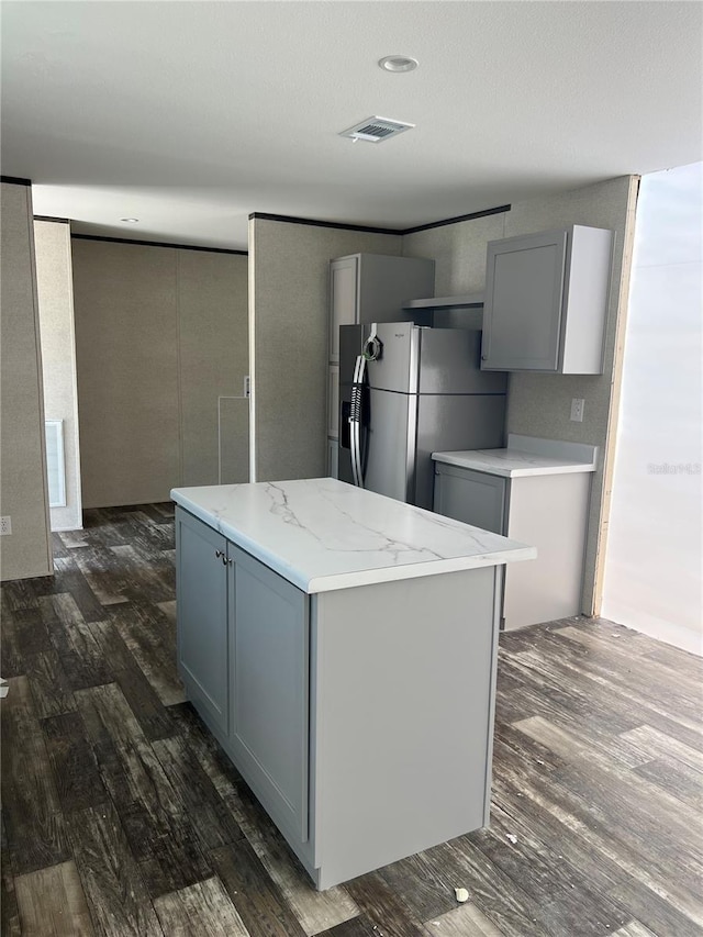 kitchen featuring visible vents, gray cabinets, freestanding refrigerator, and dark wood-style floors