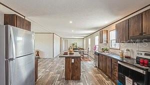 kitchen featuring stainless steel appliances, a kitchen island, exhaust hood, dark brown cabinets, and dark wood finished floors