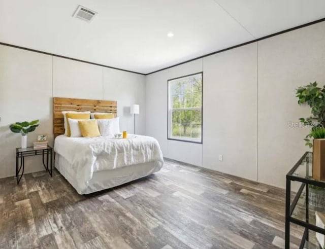 bedroom featuring crown molding, visible vents, and wood finished floors