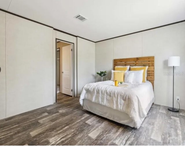 bedroom featuring visible vents, wood finished floors, and ornamental molding