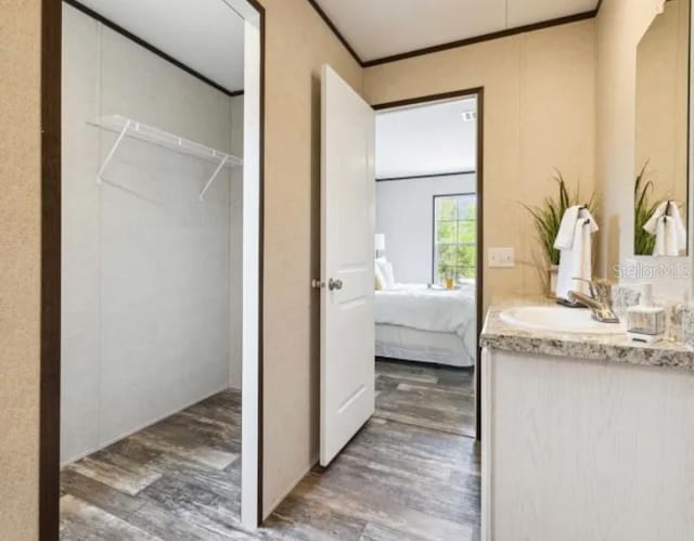 bathroom with ensuite bath, wood finished floors, vanity, and crown molding