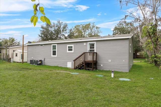 rear view of house featuring cooling unit and a lawn