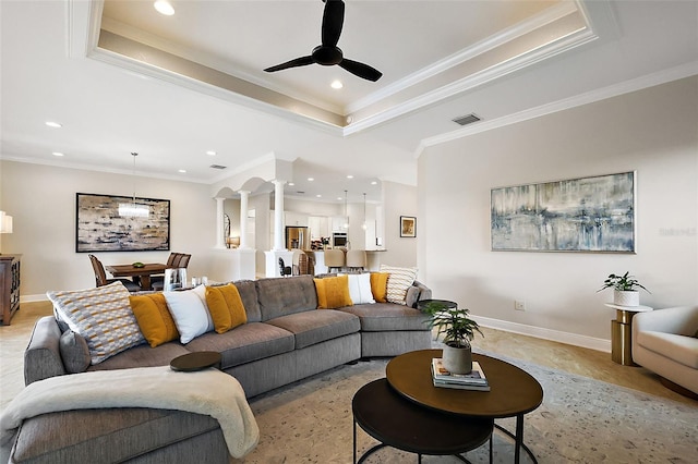 living room with a tray ceiling, decorative columns, visible vents, and baseboards