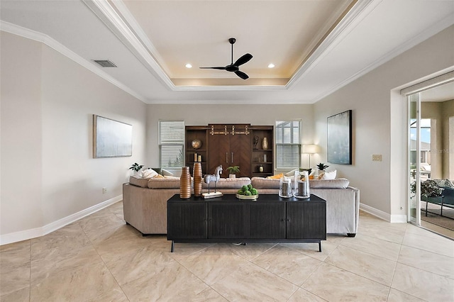 living area with ornamental molding, a raised ceiling, a ceiling fan, and baseboards