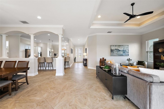 living room with a wealth of natural light, visible vents, decorative columns, and ceiling fan