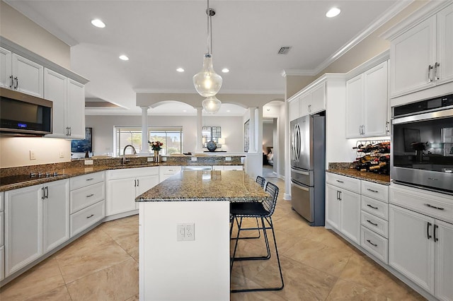 kitchen featuring a breakfast bar, appliances with stainless steel finishes, arched walkways, and crown molding