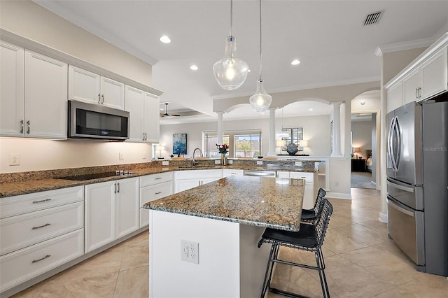 kitchen with decorative columns, visible vents, white cabinets, a peninsula, and stainless steel appliances