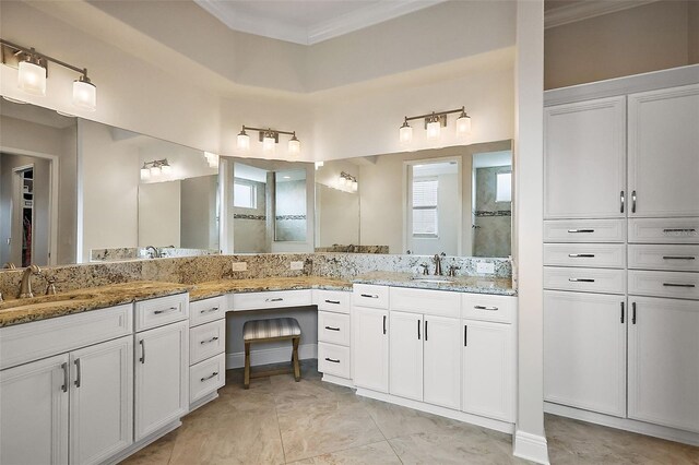 bathroom with crown molding, a shower, two vanities, and a sink